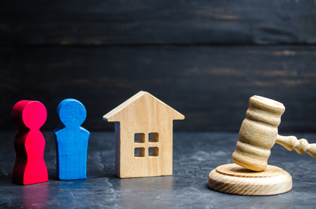 division of property by legal means. clarification of ownership of the house. wooden figures of a man and a woman are standing near the judge's gavel. trial, conflict. court. divorceの写真素材