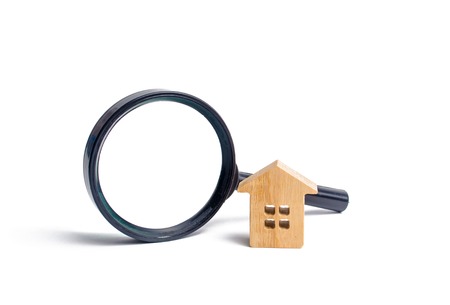 Wooden house and magnifying glass on a white background. Buying and selling real estate, building new buildings, offices and homes. House search. The concept of urban planning, infrastructure projectsの写真素材