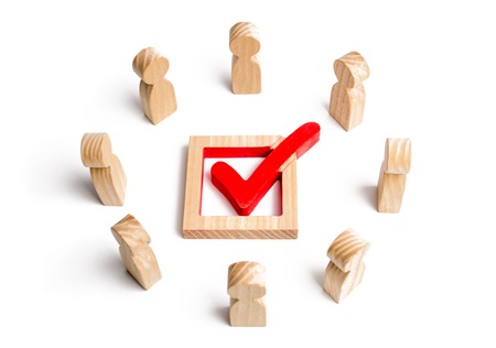 People stand in a circle and look at the check mark in the box. election, poll or referendum. Voters participate in elections of parliament or president. Decision making. Poll people. Selective focusの写真素材