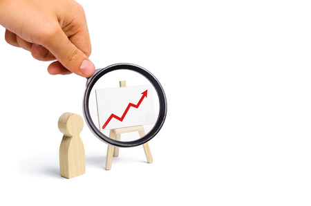 A person is standing near a chart with a red up arrow. Financial success and achievement. Business report and idea. Summarizing. Analysis and market research. Education in economics. Statistical dataの写真素材
