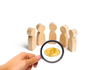 Wooden figurines of people are standing around a bitcoin coin on a white background. cryptocurrency and blockchain technology. Decentralization of the financial system, execution of transactions.の写真素材