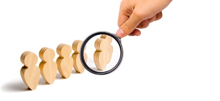 Magnifying glass is looking at the Wooden figures of people stand in the formation. Candidate, elected employee, the best of all. Selection, the choice of talent. Business training, Selective focusの写真素材