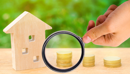 Concept investment in real estate. Saving money to buy a new home. Wooden house and stacks of coins from small to large. Buying, renting apartments. Mortgages and tax on housing / propertyの写真素材