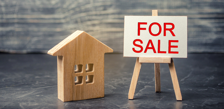 wooden house and dollars with the inscription "for sale". sale of property, home. affordable housing. sale of apartments. real estate agent services.の写真素材