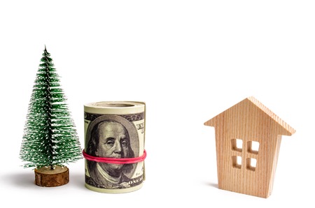 Wooden house and Christmas tree and dollars. Christmas Sale of Real Estate. New Year discounts for...