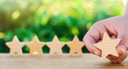 Five wooden stars. Get the fifth star. The concept of the rating of hotels and restaurants, the evaluation of critics and visitors. Quality level, good service. selective focusの写真素材
