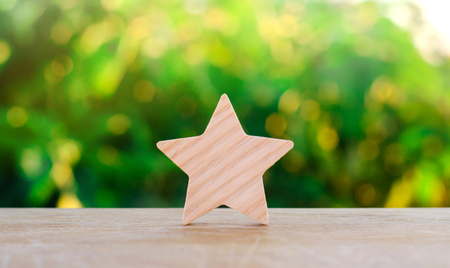 One wooden star. Rating hotel, restaurant, hotel. Overview. appreciation of the critic. Negative feedback. poor quality of service. green bokeh background. selective focusの写真素材