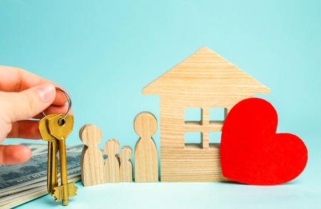 Family stands near the house. Affordable housing. Real estate concept. Buying and selling homes. Rent apartment. Sale of property. Mortgage and payment of taxes. Debt and loan. Purchase. Home sold.の写真素材
