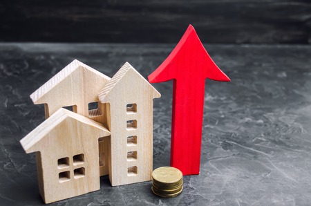 Wooden houses with a red arrow up. concept of high demand for real estate. increase energy efficiency of housing. rise in house prices. property. population growth. Increase in the real estate marketの写真素材