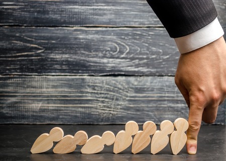 Leader businessman stops falling dominoes. Strong and reliable boss. Difficulties in business and their solution. Support team. The fall of the crumbling business is saved by leader.の写真素材