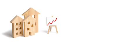 Wooden houses stand with red arrow up. Growing demand for housing and real estate. The growth of the city and its population. Investments. concept of rising prices for housing or rent. bannerの写真素材