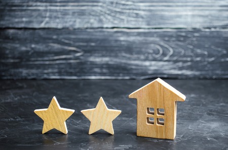 Two wooden stars and a house. Two star hotel or restaurant. Review of the critic. Quality of service and level of service. Rating of houses and private property. Evaluation of critics and visitorsの写真素材