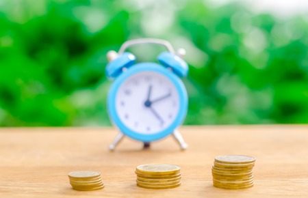 Alarm clock and money on green bokeh background. The concept of Time is money. Business financial...