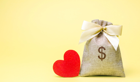Bag with money and red heart. Valentine's Day. Saving money. Accumulation. Buying gifts to your loved one. Preparation for the holiday.の写真素材