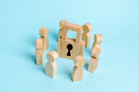 Wooden figures of people stand around a padlock. The concept of security and security, the protection of personal data and privacy policy. Bank secrecy, medical secret. Lock without keyの写真素材