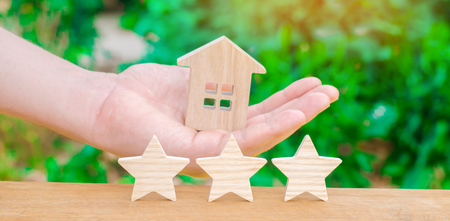 The concept of selling and buying a home. Valuation of property. High quality and reliable purchase agreement. Trust and good service. Three stars and a hand holding a house.の写真素材