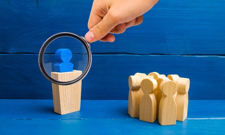 Magnifying glass is looking at the leader from the rostrum speaks a speech addressing a crowd of people. Business concept of leader and leadership qualities, crowd management, political debate.の写真素材