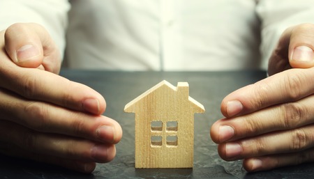 Insurance agent protects the house with a gesture of protection. The concept of property insurance protection and housing. Security and safety in the home. Life insurance and family. Real estateの写真素材