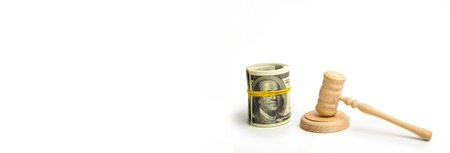 A wooden judge hammer and a bundled bundle of dollars on a white background. Franklin's eyes on the banknote are covered with an elastic band. The concept of corruption in the judicial sphere. bannerの写真素材