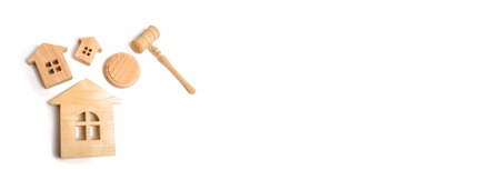 Three wooden houses and a hammer of the judge on a white background. Court cases on property and real estate. Confiscation and nationalization, real estate scam. Issuance of permits for construction.の写真素材