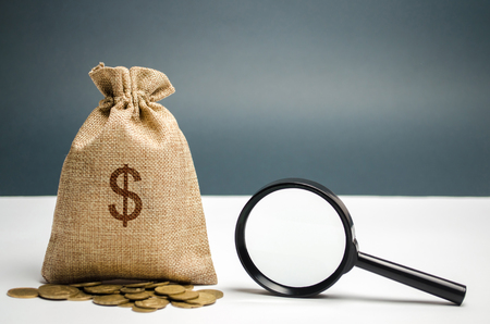 Money bag with dollar sign and magnifying glass. The concept of finding sources of investment and sponsors. Charitable funds. Startups and crowdfunding. Search for available loans. Find a job.の写真素材