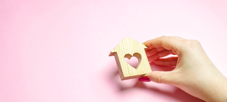 A girl holds a house and heart in her hands. The concept of affordable housing. A dream is to buy a house. Accumulation on the apartment. Property rental. Sale and mortgage real estate. Sweet Homeの写真素材