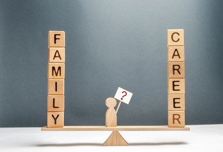 The man on the scales with a poster and a sign of questions. choice between career and family. The concept of paying attention to the family, promotion at work, overtime and exhausting work. Obsessionの写真素材