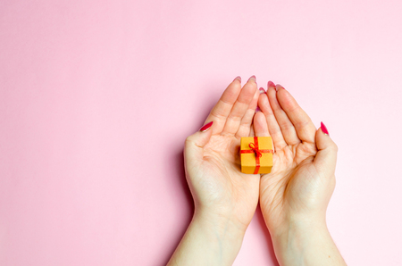 The girl holds a gift in the palms, hands. Concept Presents for your loved one on Valentine's Day. Make it nice to pick the right gift. Love and romance. Online shopping, discounts and promotionsの写真素材