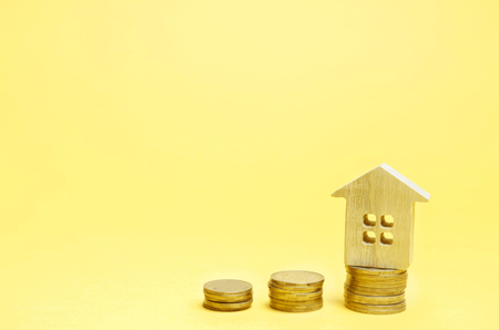 Stacks of coins and a wooden house. The concept of saving money for buying a home. Buy an apartment, real estate. Payment of rent for the apartment. Property tax repayment. Focus on the house.の写真素材