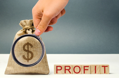 Money bag and wooden blocks with the word Profit. The concept of accumulation of profit. Income distribution. Planning a business. To save money. Business and Finance. Revenue Analyticsの写真素材