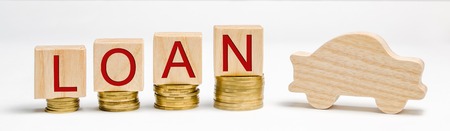 Wooden blocks with coins and the word Loan and a car. The concept of buying a car on credit. Debt for auto. Vehicle. The accumulation of money. Savings. Automobile. Debt growthの写真素材