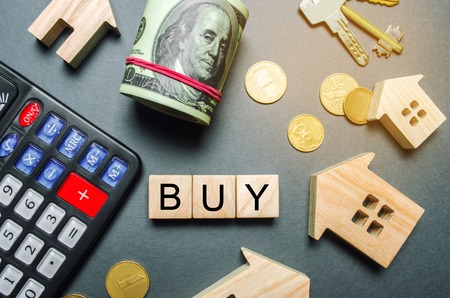 Wooden houses, a calculator, keys, coins and blocks with the word Buy. Buying a house or apartment. Buy property/ affordable housing. Realtor Services. Cost calculation. Flat layの写真素材