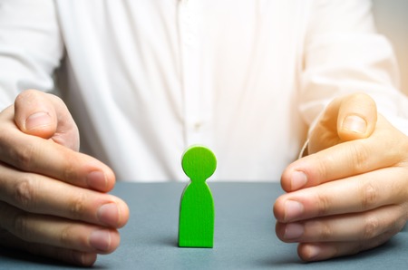 The insurance agent protects the green man figure. The concept of support and care. Psychological help. Work with staff. Life and health insurance. Hiring and finding talent. Development of skillsの写真素材