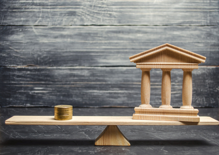 A miniature bank and money on the scales. The concept of successful investment in the bank. Credit / Loan / Deposit.The concept of dividend payments. Banking system, investment in the economyの写真素材