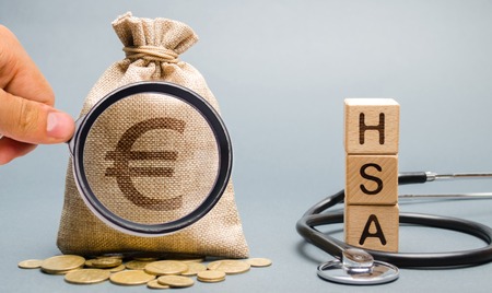 Wooden blocks with the word HSA and money bag with stethoscope. Health savings account. Health care. Health insurance. Investments. Tax-free medical expenses. Coins and euro signの写真素材