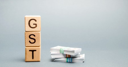 Wooden blocks with the word GST (Goods & Services Tax) and money. Tax, which is imposed on the sale of goods and servicesの写真素材