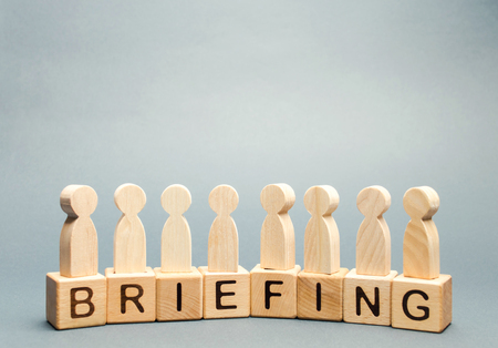 Wooden blocks with the word Briefing and a crowd of employees. Short press conference informative. Meeting. Cooperation. Develop a business strategy. Experience exchange. Teamwork. Business planningの写真素材