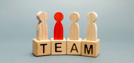 Wooden blocks with the word Team and a crowd of workers with a leader. The concept of a strong reliable business team. Teamwork. Team management. Choosing a new mentor. Wooden figures of peopleの写真素材