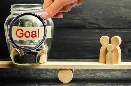 Family and glass jar with the inscription Goal. The concept of achieving family goals. The accumulation of money for the execution of targets. Achievement and motivation. Family Budget Planningの写真素材
