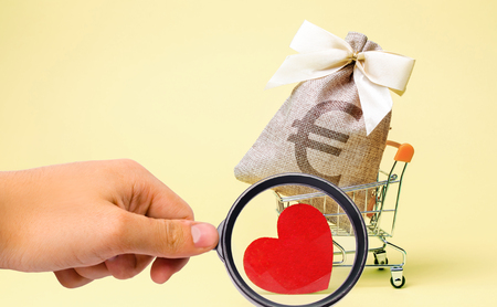 Bag with euro sign and red heart in a supermarket trolley. Charity. Donation. Social help. Volunteering. Saving money. Accumulation. Buying gifts to your loved one. Valentine's Dayの写真素材
