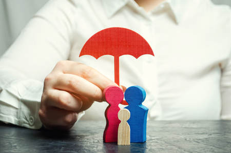 Insurance agent services. Concept of life and health insurance. Social protection of people. Security and support. Miniature wooden figures of people in the form of a familyの写真素材