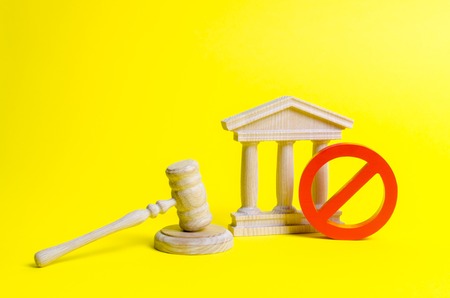 Wooden judge hammer and government building on a yellow background. Court. Concept of the state judicial system. Laws and the constitution, lack of Supremacy of rights and freedomsの写真素材