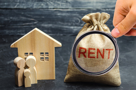 A bag with money and the inscription Rent and the family is standing near the house. Removable housing. Rental of property, apartments. services of a realtor. affordable housing, rental prices.の写真素材