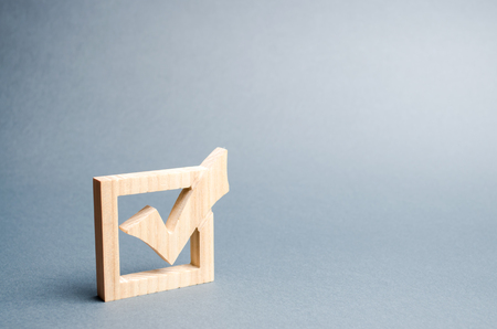 wooden checkmark for voting on elections on a gray background. Presidency or parliamentary elections, a referendum. Survey of the population, statistics, task. Democracy and freedom. Selective focusの写真素材