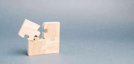 Wooden puzzles on a gray background. One puzzle is different. Individual opinion. Stand out from the crowd. Uniqueness. Divergent views. Different concepts to other people. Place for text.の写真素材