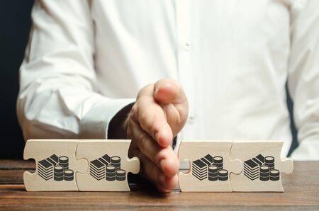 Businessman separates the wooden puzzle with a picture of money. The concept of financial management...