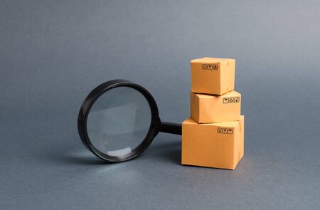 Cardboard boxes and a magnifying glass. Warehouse of finished products and equipment. buying and selling goods and services, internet commerce, online shopping, trade and turnover. Import and exportの写真素材