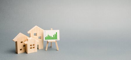 Wooden houses with a stand of graphics and information. Growing demand for housing and real estate. growth of the city and its population. Investments. banner, place for text. Selective focusの写真素材