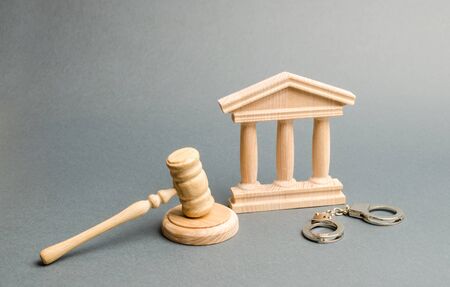 Handcuffs, judge's gavel and courthouse. Protection of the defendant in the criminal case. Protection strategy. verdict on the case. Investigation of the crime. judicial system, execution of sentencesの写真素材