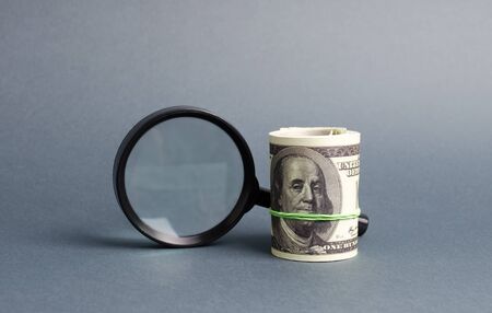 Magnifying glass and a bundle of money. Concept of fundraising, attracting investments. Loan to paycheck, urgent loans. The study of sources of profit, money laundering, offshore. Financial monitoring